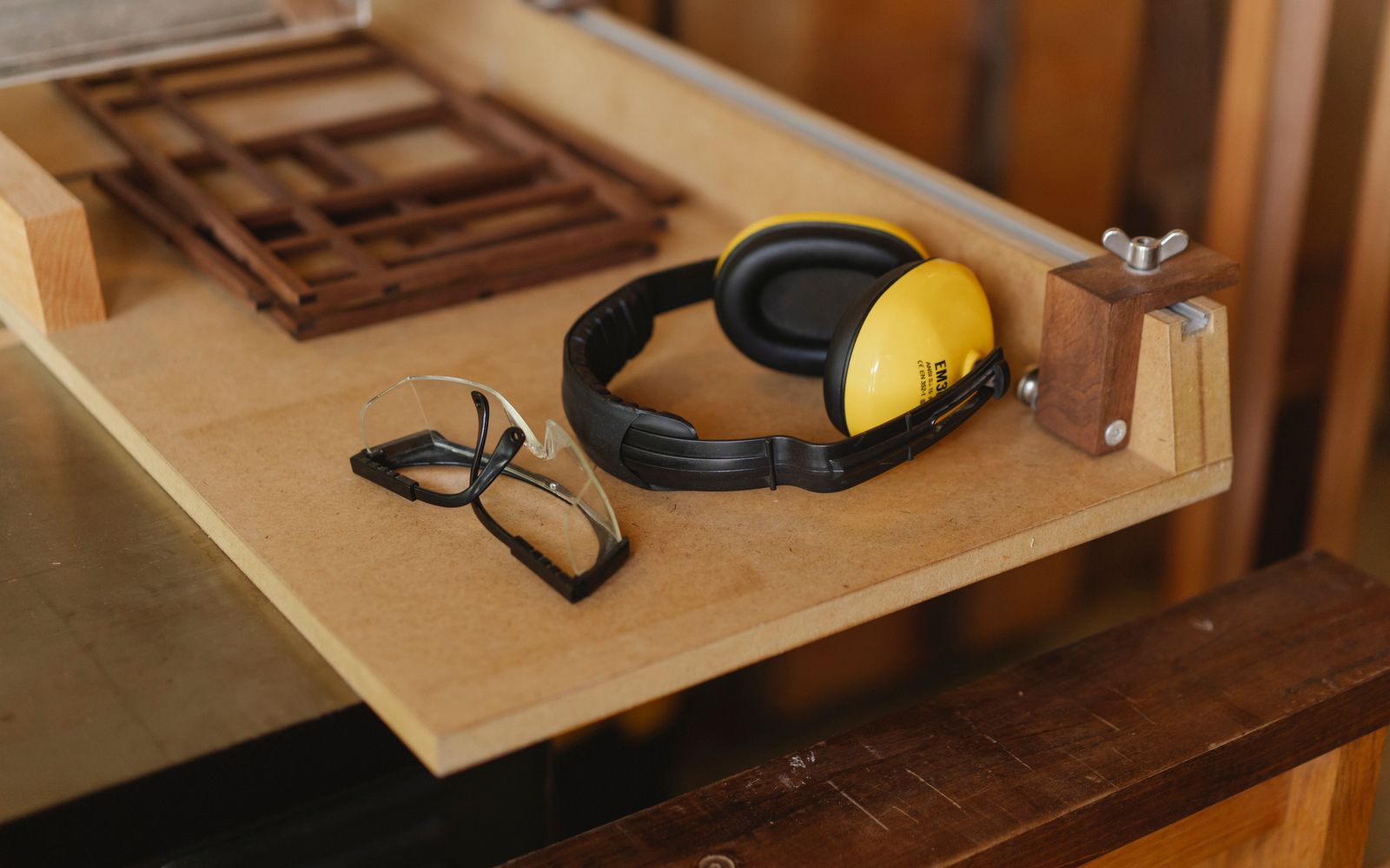Protective earmuffs and safety glasses on a woodworking bench